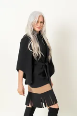 Chaquetón negro italiano con mangas irregulares, lazo y flecos en el ruedo.