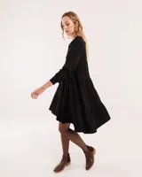 Vestido corto negro con cuello camisero, mangas 3/4 con elástico en los puños y falda con volados.