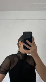 Body negro de terciopelo acanalado con detalles de microtul y encaje, cuello alto y espalda descubierta.