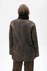 Gamulán reversible de cuero ovino con acabado gastado, diseño de corte recto, cuello alto y cierre frontal con cremallera. Cuenta con bolsillos frontales amplios.