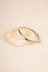 Set de dos pulseras rígidas con forma cuadrada, una color crema con efecto marmolado y otra plateada.