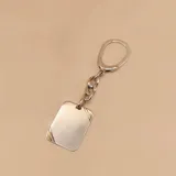 Llavero rectangular de plata 925 con detalles en oro. Incluye una placa rectangular con bordes dorados, un tramo de cadena gruesa plateada y un aro para llaves plateado.