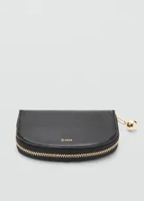 Billetera de poliuretano color negro, de diseño semielíptico, cierre con cremallera y detalle de tirador esférico metálico dorado. Cuenta con el logotipo de la marca estampado en color dorado en el frente.