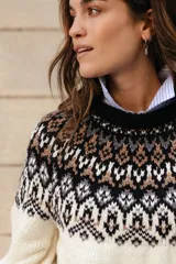 Sweater de lana con diseño de jacquard en la parte superior, cuello redondo, mangas largas y puños acanalados. Presenta un corte holgado con tajos laterales y un diseño ligeramente más corto en la parte delantera.