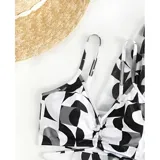 Conjunto de traje de baño de tres piezas con estampado de hojas tropicales en tonos blanco y negro. Incluye un top tipo tankini con cordón ajustable en el centro, un short de tiro alto y una camisa abierta de manga larga tipo salida de baño.