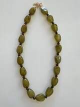 Collar de cuentas ovaladas de resina con efecto marmolado en tonos marrones, unido por pequeñas esferas y cierre metálico dorado.