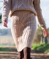 Falda midi de tiro alto tejida en lana merino color beige, con diseño de trenzas y rombos texturados en relieve.