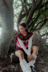 Chaleco tejido de punto con diseño multicolor en bloques, cuello redondo y terminaciones acanaladas. Presenta un patrón geométrico en tonos bordó, rosa, celeste, marrón y crema.