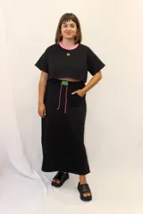 Falda larga de estilo deportivo confeccionada en tejido de algodón y poliéster. Presenta cintura elástica con cordón de ajuste en color fucsia, bolsillos laterales y un aplique decorativo de acrílico en la parte frontal.