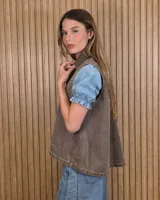 Chaleco de denim 100% algodón en color negro gastado, con cuello camisero, cierre frontal de botones metálicos y bolsillos delanteros con solapa.