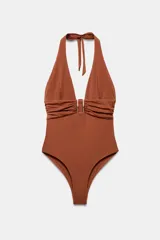 Malla enteriza marrón con escote halter y pronunciado escote en V. Cuenta con copas extraíbles y detalle fruncido en el pecho con una pieza metálica rectangular central.