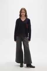 Sweater de tejido de punto con diseño de trenzas, cuello en V y detalles de rayas en contraste en cuello, puños y ruedo. Presenta un número bordado en el frente y tiene un corte holgado.