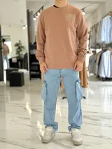 Buzo color camel de corte clásico, con cuello redondo, mangas largas y estampa gráfica en la espalda con diseño de arte clásico, el texto "Simple" y "Keep it".