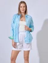 Camisa de algodón estampada en tonos celeste y blanco, con cuello con solapa, abertura central con botones y mangas largas con puños en contraste.