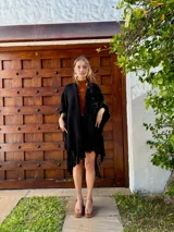 Ruana tejida en lana, de color negro, con diseño de flecos en los bordes inferiores.