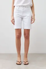 Bermuda de jean color blanco, con cinco bolsillos, corte a la rodilla y cierre frontal con botón y cremallera.
