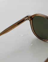 Lentes de sol con armazón geométrico color mostaza y lentes verdes polarizadas.