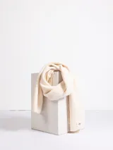 Bufanda de punto acanalado en color beige claro, con diseño clásico y etiqueta pequeña en el extremo.