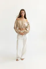Blusa corta color salmón, con escote recto con elástico, mangas largas abullonadas con elástico en los puños y corte crop.