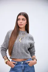 Sweater de punto gris con diseño de trenzas verticales, cuello redondo y corte cropped.