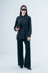 Camisa de corte clásico con estampa de lunares blancos sobre fondo negro, manga larga con puños abotonados y bolsillo frontal.