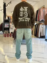 Buzo oversize de cuello redondo en color marrón con efecto gastado, con gran estampado en la espalda de estrellas y el texto VCP CNPT.