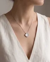 Collar de acero con dije en forma de trébol relleno de nácar blanca y borde con incrustaciones de circones.