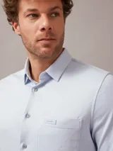 Camisa celeste de algodón orgánico, corte slim fit, con cierre frontal de botones, bolsillo de parche en el pecho y logo de Calvin Klein en el lateral.