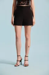Short negro de tiro alto con cinto incorporado del mismo género con hebilla redonda forrada, bolsillos laterales y dobladillo en las piernas.