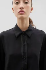 Camisa de corte holgado y diseño clásico, confeccionada en tela satinada con un sutil estampado floral tono sobre tono. Presenta cuello camisero, cierre frontal con botones y mangas largas con puños rectos.