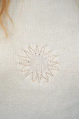 Sweater de tejido de punto color marrón, crop, con mangas largas y cuello redondo. Presenta un pequeño bordado rojo en el pecho y en el borde inferior.