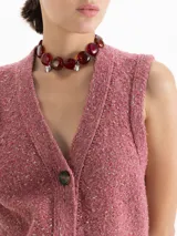 Chaleco de punto con escote en V y cierre frontal de botones. Presenta un diseño en color rosa con sutiles destellos metalizados y terminaciones en ribb elástico en sisa y cintura.