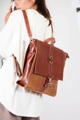 Mochila de cuero vacuno color marrón con detalles en cuero texturizado. Tiene mosquetón de seguridad exterior, cierre interior, dos bolsillos interiores (uno con cierre y otro para celular), sujetador de llaves, forro completo y tiras ajustables. Se puede usar como mochila o como cartera.