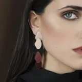 Par de aros colgantes con piezas abstractas de acrílico en color negro, marrón, rojo, dorado y rosa pálido.