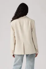 Blazer holgado color beige, de corte clásico con solapas de muesca, cierre frontal de un botón, bolsillos con solapa y mangas largas con botones en los puños.