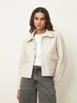 Chaqueta corta de paño color azul oscuro, con cuello camisero, cierre frontal con botones metálicos dorados y bolsillos frontales con solapa.