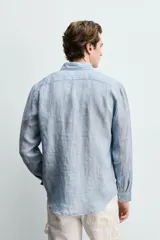 Camisa celeste de lino de corte regular fit, con cuello abotonado, manga larga y cierre frontal de botonadura.