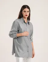 Camisa oversized con terminación metalizada color gris plomo. Tiene botones a tono en el delantero, largo por debajo de la cadera y tajos a los costados.
