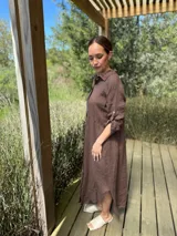 Vestido camisero largo de lino blanco, con cuello camisero, manga corta enrollada y cierre frontal de botones de nácar. Presenta aberturas laterales en el bajo.