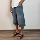 Bermuda de jean estilo baggy, de corte amplio y largo por debajo de las rodillas, con acabado desgastado.