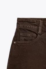 Shorts de jean color marrón oscuro, de tiro medio y corte mom fit. Con cinco bolsillos, cierre frontal con cremallera y botón.