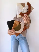 Billetera de cuero negro con sistema de cierre con broche y monedero externo. Presenta un diseño texturizado en la solapa frontal.