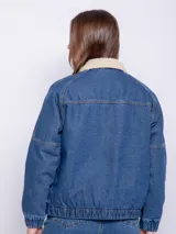 Campera de jean color blanco con corderito en el cuello y en el interior. Cuenta con dos bolsillos en la parte delantera, botones metálicos y elástico en el bajo.
