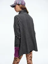 Buzo tejido de silueta holgada en color beige, con cuello alto y mangas largas. Presenta tajos laterales en el ruedo que aportan movimiento a la prenda.