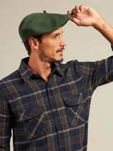 Boina azul marino de paño con visera pequeña y botón decorativo en la parte superior.