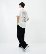 Remera de corte relajado color blanco, con cuello redondo y manga corta. Presenta un estampado pequeño en el centro del pecho con la inscripción 'Most Wanted' y el diseño de los Hermanos Metralla.