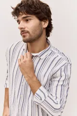 Camisa de manga larga de lino con diseño a rayas en tonos celestes y blancos, cuello camisero clásico y cierre frontal de botones.