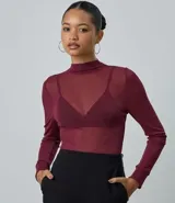 Blusa de manga larga confeccionada en punto con tule y transparencia, con cuello alto y acabado con sutiles puntos de brillo. Presenta un diseño ajustado al cuerpo.