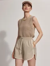 Short deportivo color beige con ribetes blancos, cintura elastizada y corte holgado.