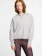 Sweater de punto gris claro, con cuello polo y tapeta de dos botones. Presenta un acabado de pelo suave y terminaciones ajustadas en puños y ruedo.